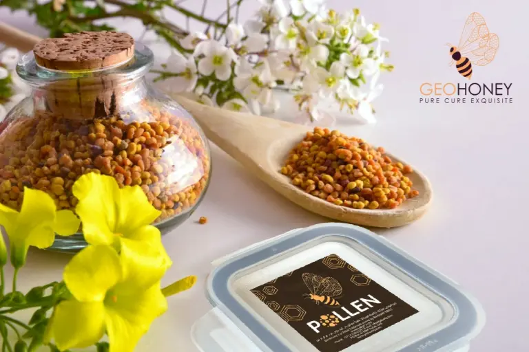 A jar of bee pollen with a wooden spoon, surrounded by flowers and honeycomb.